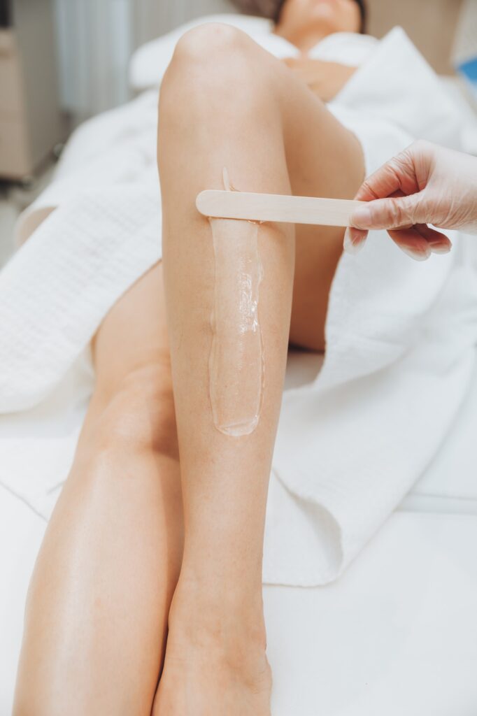 a cosmetologist puts a gel for laser hair removal on a woman's leg